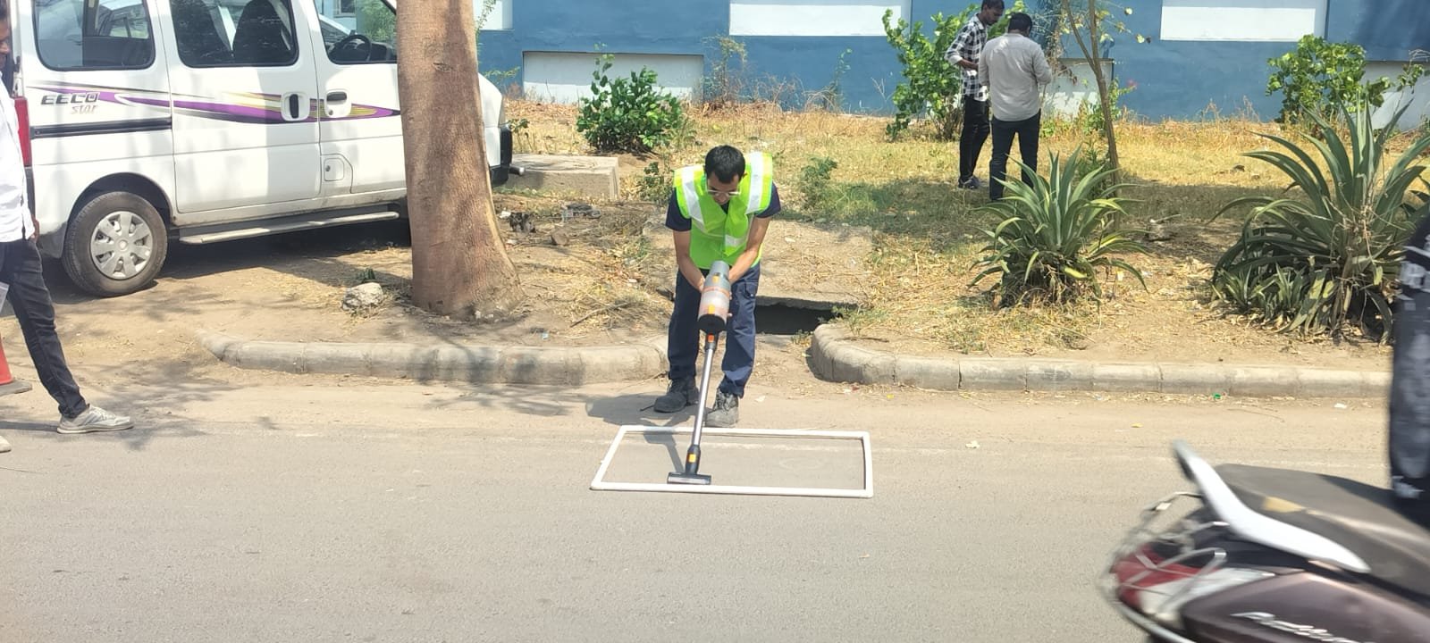 Field technician vacuum-sampling loose material from a marked road segment